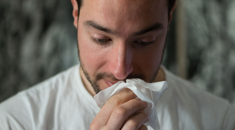 Man cleaning his nose after sneezing