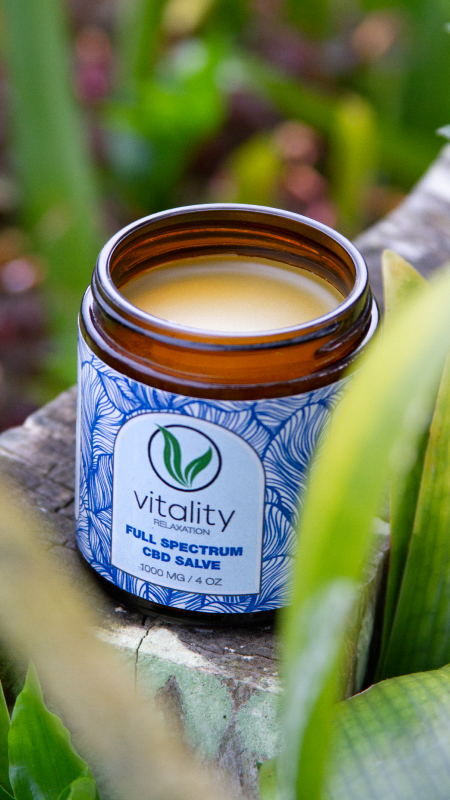 Open container of Vitality's CBD salve for relaxation on a wood block.