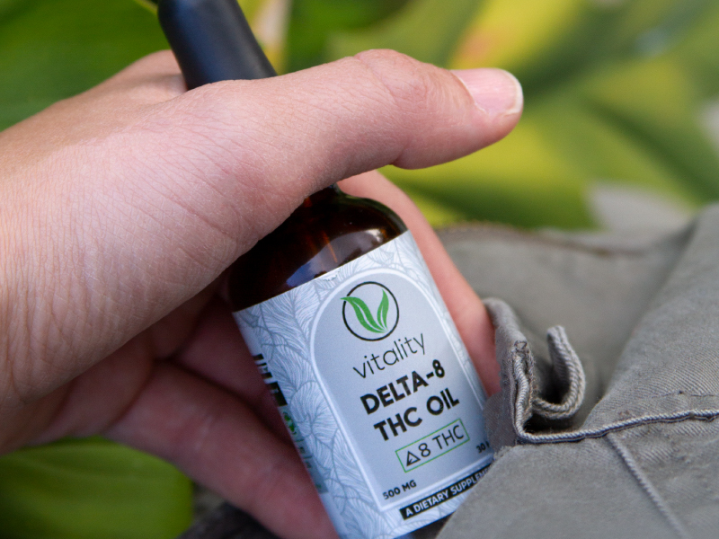 Bottle of Vitality CBD Delta-8 THC oil coming out of a shirt pocket.