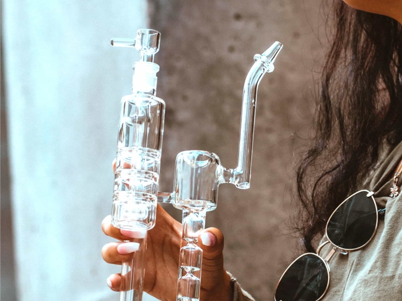Woman holding a dab rig used to consume Delta-8 shatter.