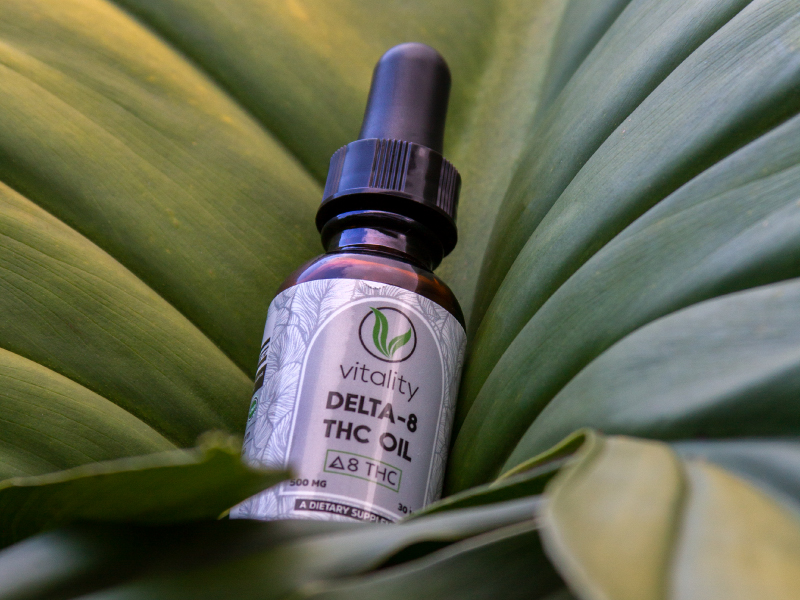 Bottle of Vitality CBD Delta 8 oil on top of a leaf.