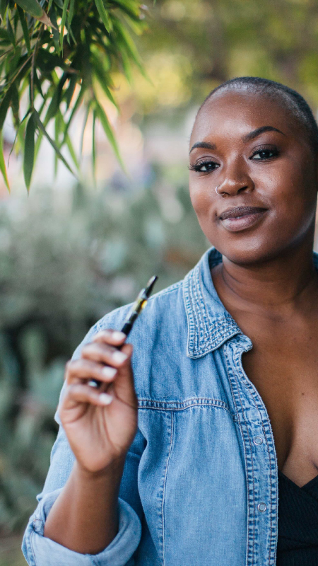 Woman holding a vaporizer with a Delta-8 cartridge attached to it.