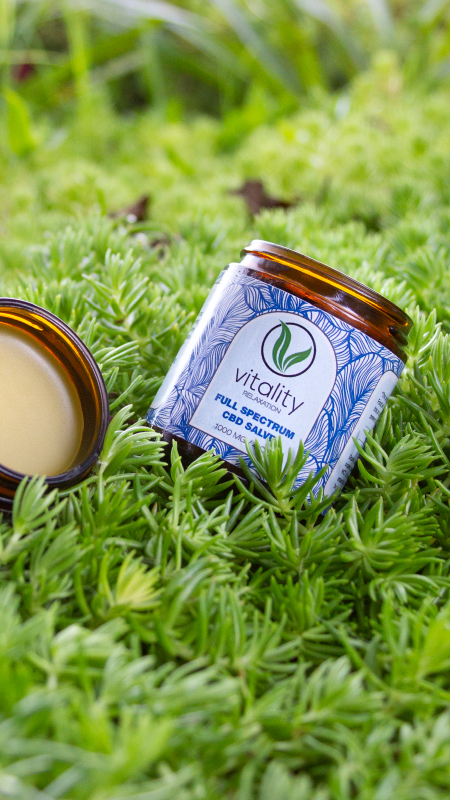 Open container of Vitality's CBD salve for relaxation on the grass.