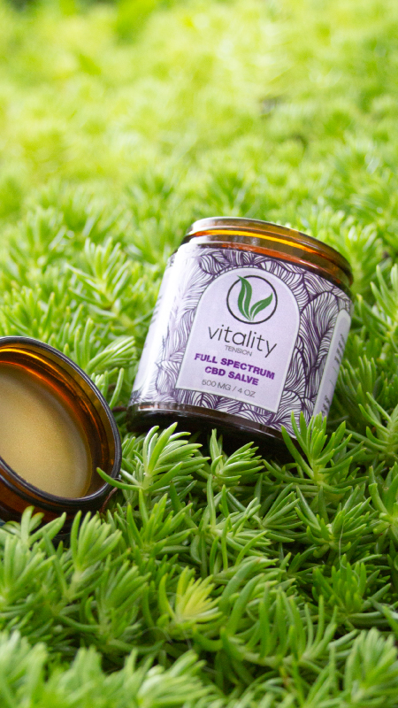 Open container of Vitality's CBD salve for tension on the grass.