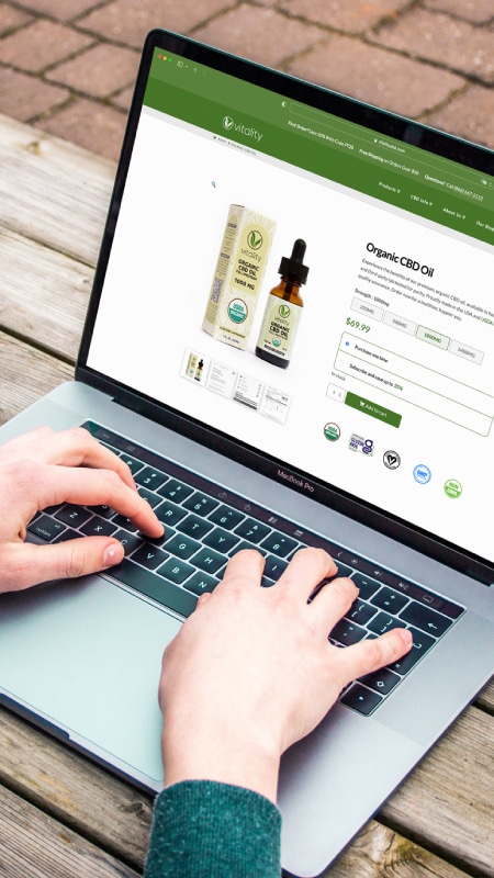 Person buying organic CBD oil on a laptop on Vitality CBD's website.