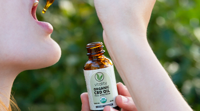 Woman ingesting Vitality's CBD oil with a dropper.