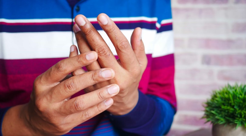 One hand rubbing another hand to relieve pain from arthritis.