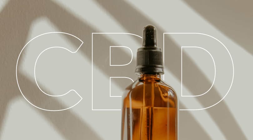 Bottle of CBD oil with "CBD" written in the background.