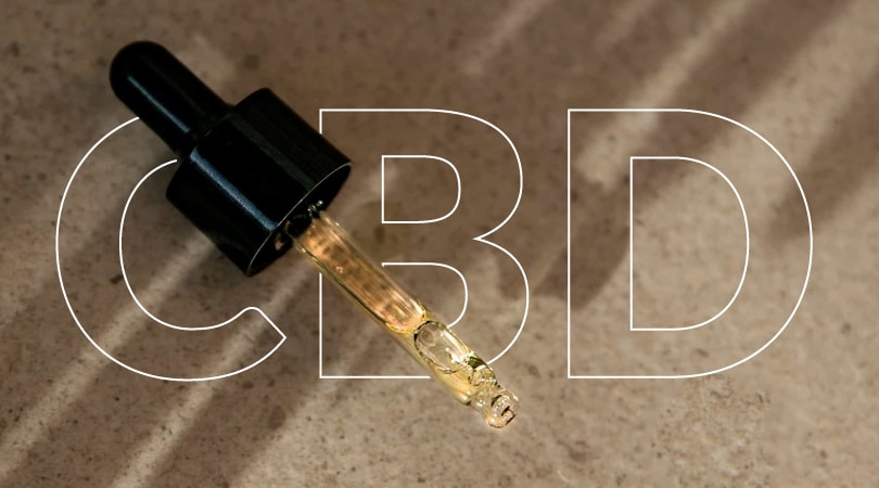 Dropper with CBD oil on a brown surface.