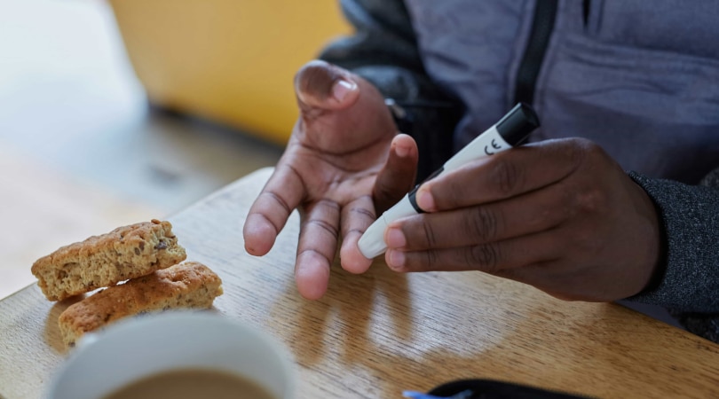 Man pinching one of his fingers with a lancet for testing blood sugar.