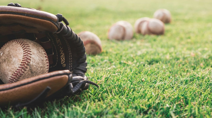 Baseball glove on the grass with a baseball on it.