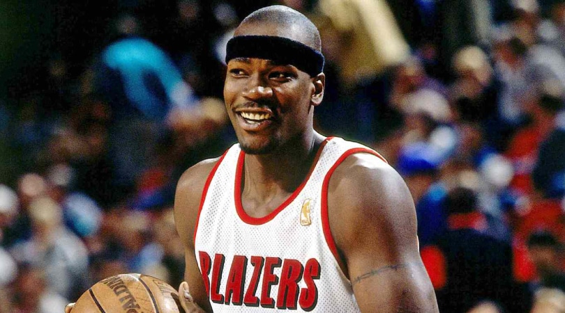 Cliff Robinson holding a basketball, wearing a Blazers jersey and a black headband.