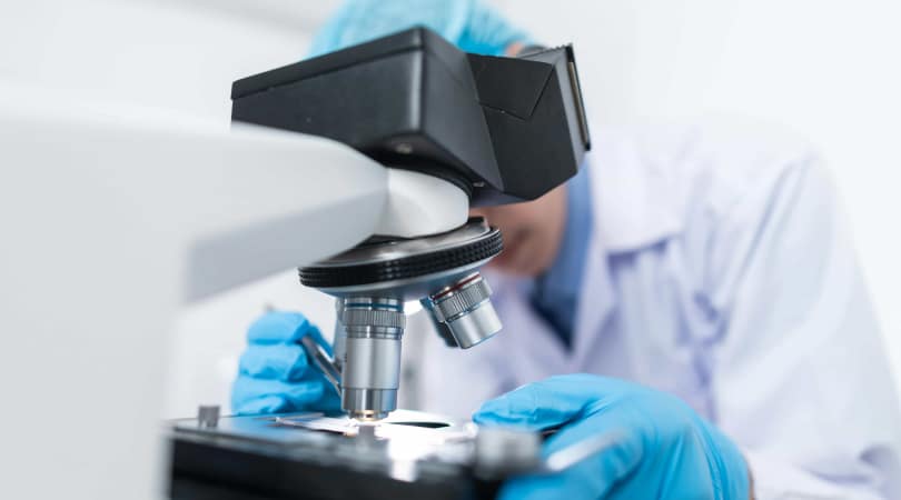 Man analyzing a sample of Delta-8 through a microscope.