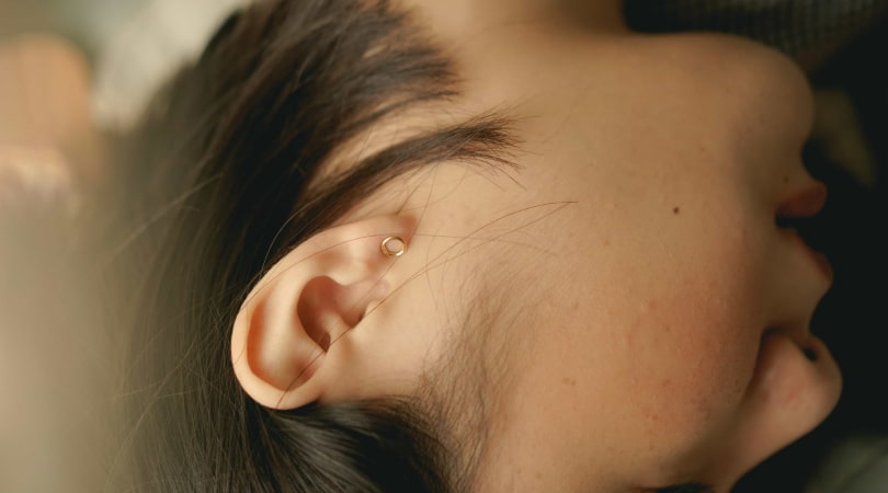 Woman's head lying sideways with her ear uncovered.