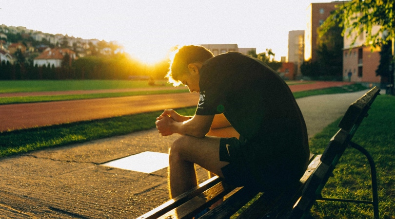 Man sitting down on a bench, having some rest after working out.