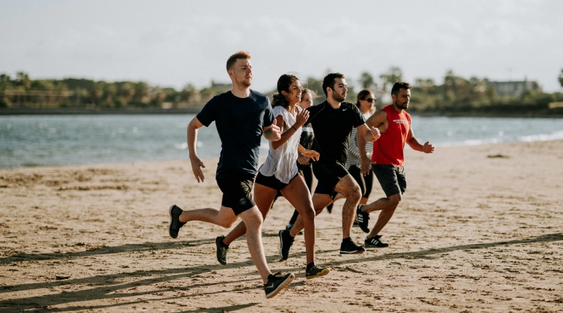 Group of people running on a beach.