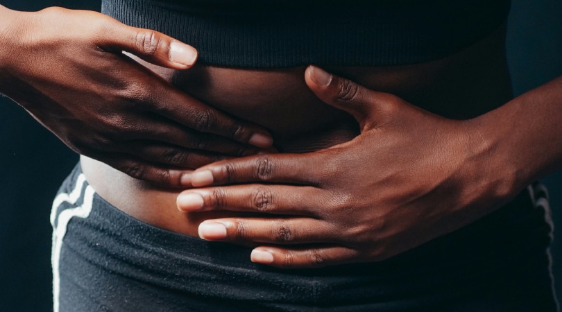 Woman with her hand on her stomach with pain from IBS.