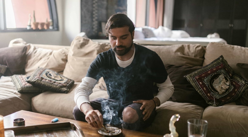 Man sitting on a couch and smoking Delta-8 flower.
